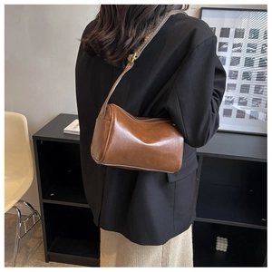 Détail du sac polochon marron avec large bandoulière tissée porté à l'épaule