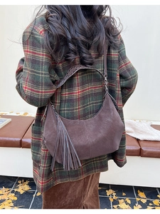 Detail of dark brown hobo bag with silver studs on strap and long side tassels