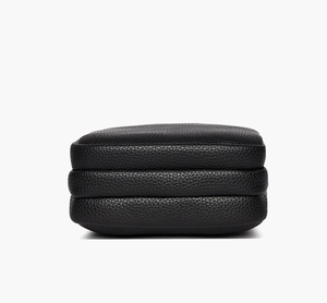 Detail view of black lychee grain leather crossbody bag with three compartment gussets