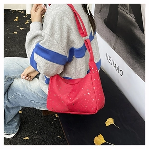 Détail d'un sac cabas rouge en velours côtelé avec motifs étoiles sur un banc