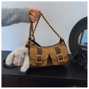 Brown suede dumpling shoulder bag with gold buckles, chain strap, and plush rabbit charm