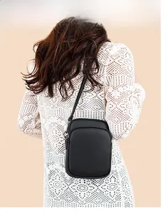 Detail view of black lychee leather mini crossbody bag with metal buckle and shoulder strap
