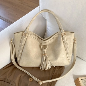 Minimalist beige oversized tote bag in textured PU leather with decorative tassels and strap