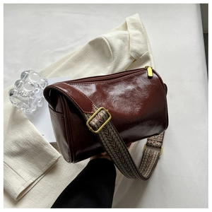 Sac bandoulière marron en cuir avec large sangle géométrique et finitions en laiton