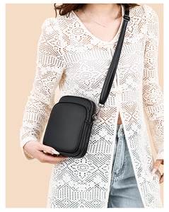 Close-up of black pebble textured leather crossbody bag with dual zipper compartments