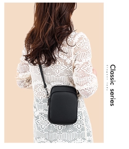 Close-up of elegant black litchi grain leather crossbody bag on white lace outfit