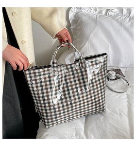 Detail view of plaid tote bag with waterproof transparent coating held by a model