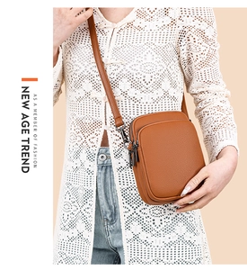 Detail of brown lychee grain leather crossbody bag with dual metal zipper compartments