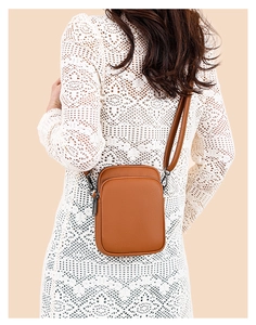 Detail of a brown lychee pattern leather crossbody bag with multi-layer zippers