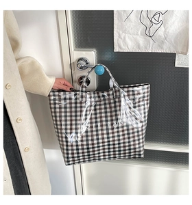 Detail of a large-capacity tote with transparent PVC layer over plaid canvas pattern