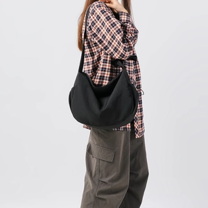 Vista laterale di una grande borsa a mezzaluna in nylon nero indossata da un modello in stile casual