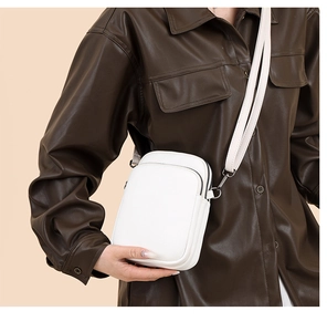 Detail view of the litchi-grain white crossbody bag with premium metal zippers and strap