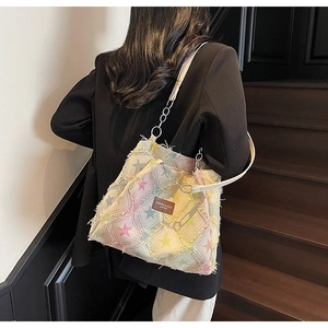 Close-up of denim tote bag with colorful stars, frayed edges and silver chain strap