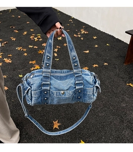 Dettaglio borsa a cilindro in denim blu lavato con borchie argentate e tasca laterale