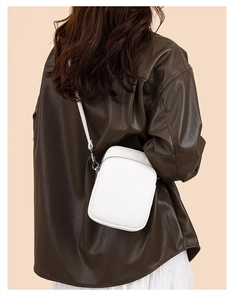 Detail of white litchi pattern leather crossbody bag with silver-black metal hardware
