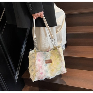 Macro detail of distressed denim tote bag with star prints and frayed edge finish