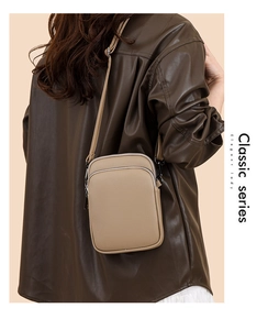 Detail view of khaki pebbled leather crossbody mini bag showing double zippers and strap