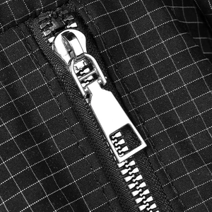 Dettaglio della cerniera in metallo argento e tessuto in nylon nero a scacchi della borsa