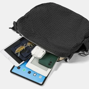 Dettaglio della grande capacità di contenere tablet nella borsa in nylon a quadri neri