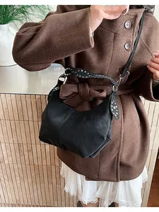 Close-up of black retro shoulder bag featuring metallic studs on wide leather strap