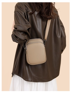 Detail of a khaki pebbled leather crossbody bag shown on a model in vintage style
