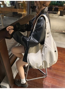 Detail of off-white canvas hobo bag with silver metallic eyelets and snap button closures