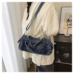 Borsa a cilindro in denim con borchie e tracolla regolabile indossata dalla modella