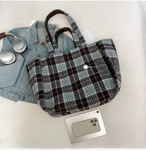 Vue à plat du sac cabas à carreaux avec anses marron et iPhone 12 pour référence de taille