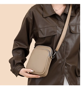 Detail of compact beige crossbody bag with textured leather and multiple zipper layers
