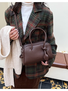 Detailaufnahme der braunen Boston-Tasche mit Litschi-Muster und Blattanhänger