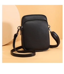 Detail of black pebbled leather mini crossbody bag with double zippers and sleek hardware