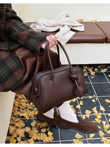 Detail der braunen Boston-Tasche aus strukturiertem Leder mit Blattanhänger