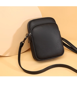Macro detail of black litchi grain leather crossbody bag with gunmetal grey zippers