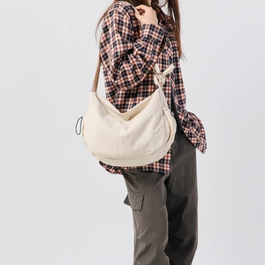 Dettaglio della borsa a tracolla in nylon crema con nodo decorativo sulla spalla