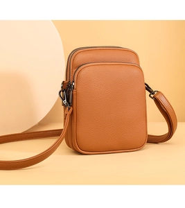 Close-up of brown pebbled leather mini crossbody bag with three zipper compartments