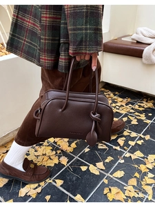 Braune Boston-Tasche aus Leder mit Knotendetail in herbstlicher Straßenszene gezeigt