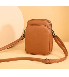Detail of tan lychee grain leather crossbody bag featuring triple zipper compartments