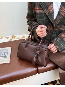 Detailansicht der braunen Handtasche mit Litschi-Muster und elegantem Knotengriff-Dekor
