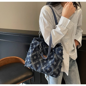Detail of distressed star patterns and vintage leather patch on denim tote bag