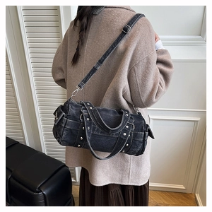 Vista dettagliata della borsa a cilindro in denim nero lavato con borchie argentate