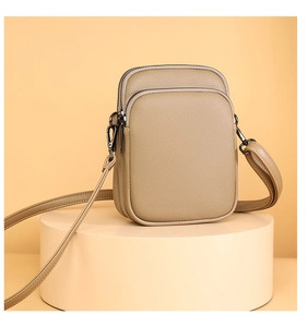Close-up of khaki crossbody bag with three zip layers and pebble grain leather texture