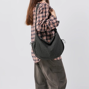 Dettaglio della borsa hobo in nylon nero a quadri con coulisse laterali e grande capacità