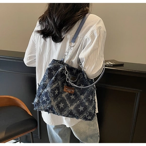 Detail of blue denim tote bag with star patterns, frayed edges and leather strap