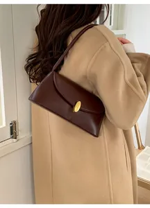 Detail shot of deep brown rectangular shoulder bag with golden oval buckle and sleek strap