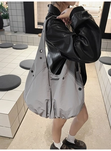 Detailed view of gray nylon tote bag with silver metal eyelets on model in black leather jacket