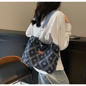 Close-up of distressed denim tote bag with star patterns and raw edges texture