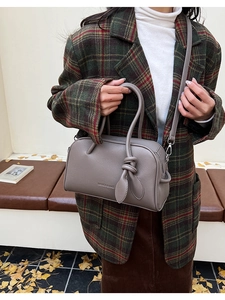 Schicke taupe Boston Bag aus Leder mit Lychee-Struktur und Knotendetail getragen von Model