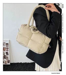Detail of beige quilted puffer handbag showing the puffy cloud texture and thick handles