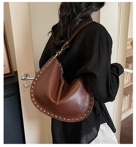 Detail of dark brown leather tote bag featuring golden rivet edges and smooth finish