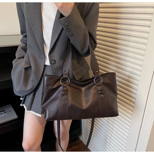 Detail of vintage soft leather tote bag with metallic ring buckles and brown shoulder strap